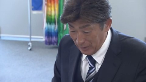 当確を伝える新聞に見入る岩本剛人氏（21日）