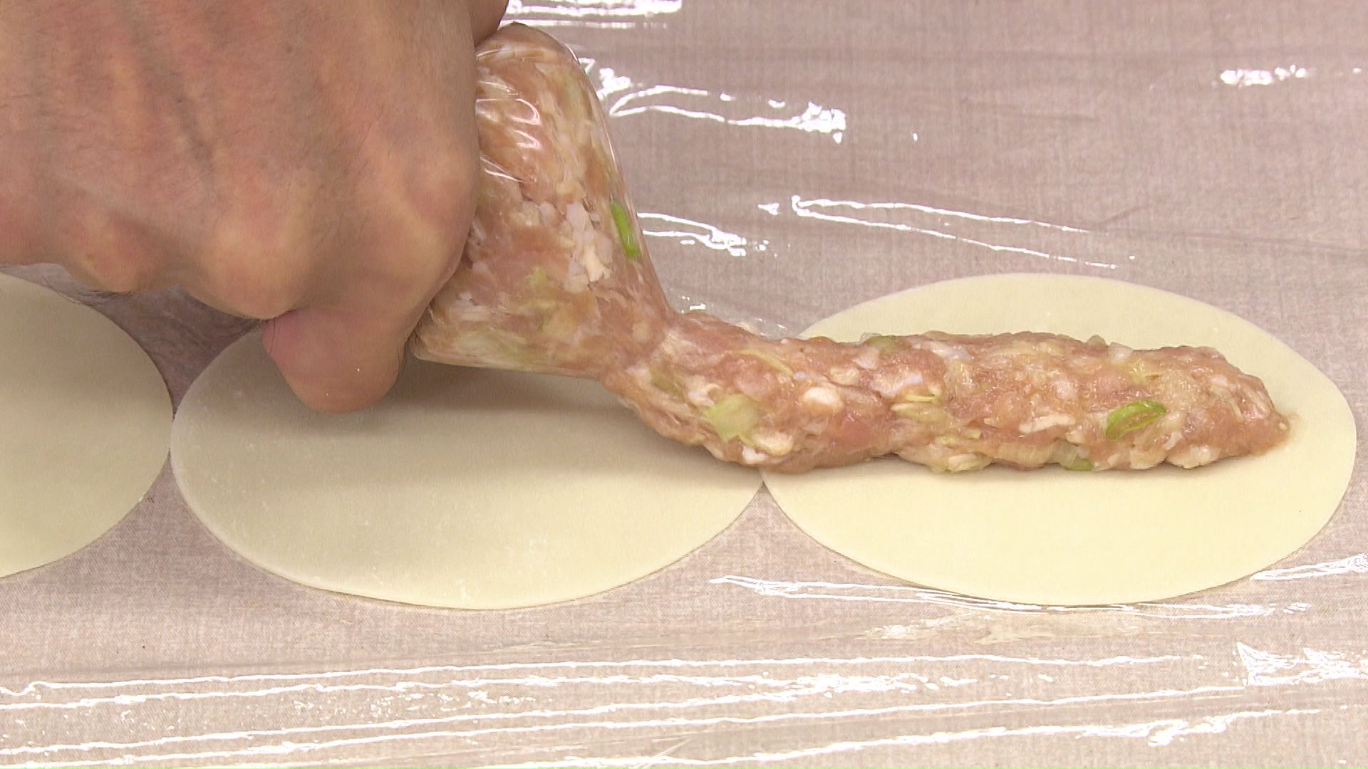 並べたギョーザの皮にタネを絞る