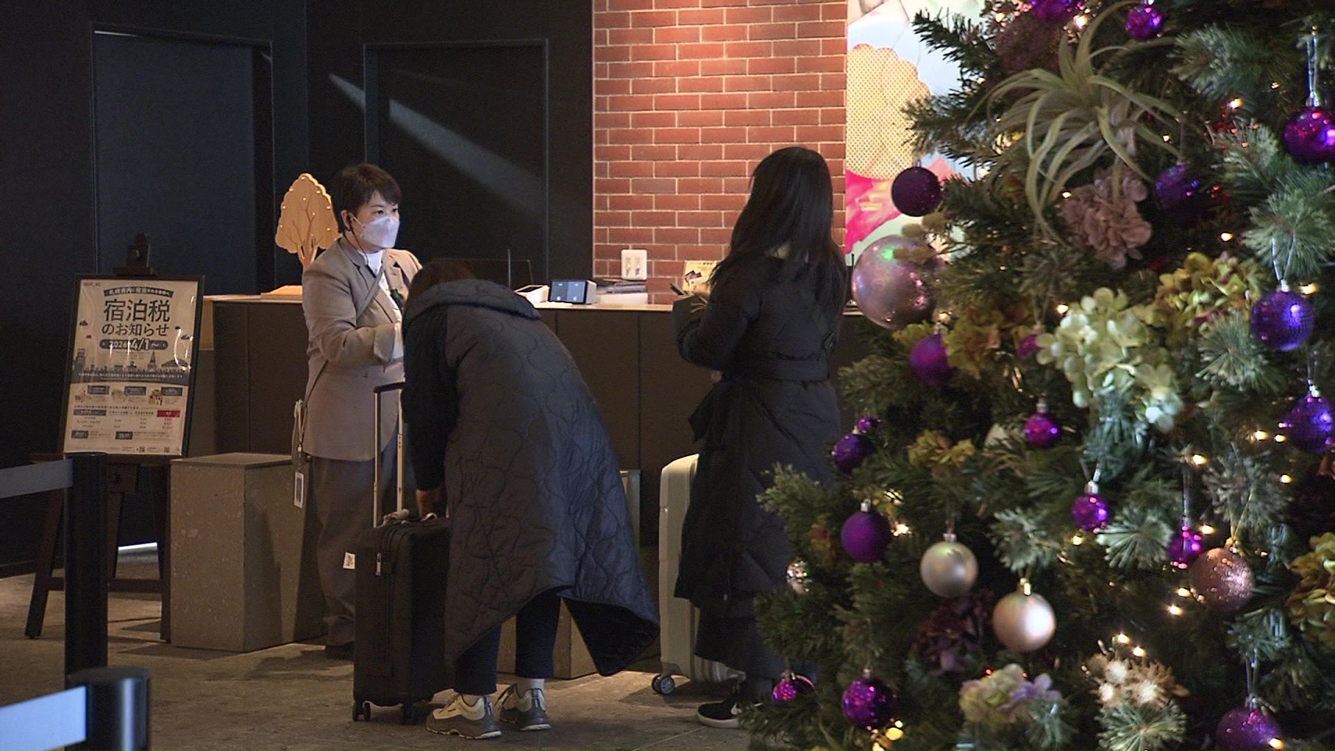 クリスマスツリーが飾られたロビーで手続きをする観光客ら
