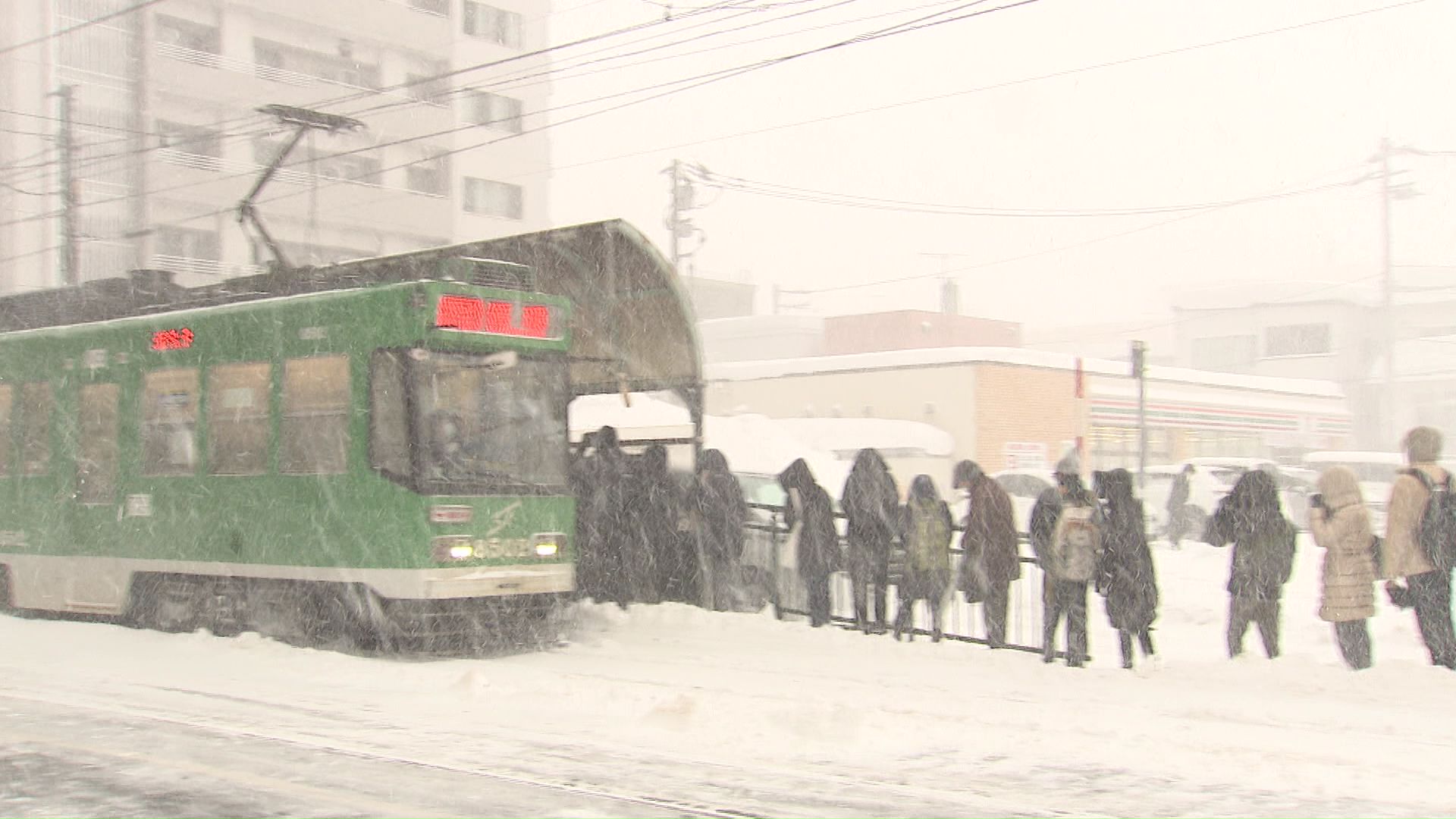 吹雪の中で電車を待つ長い列
