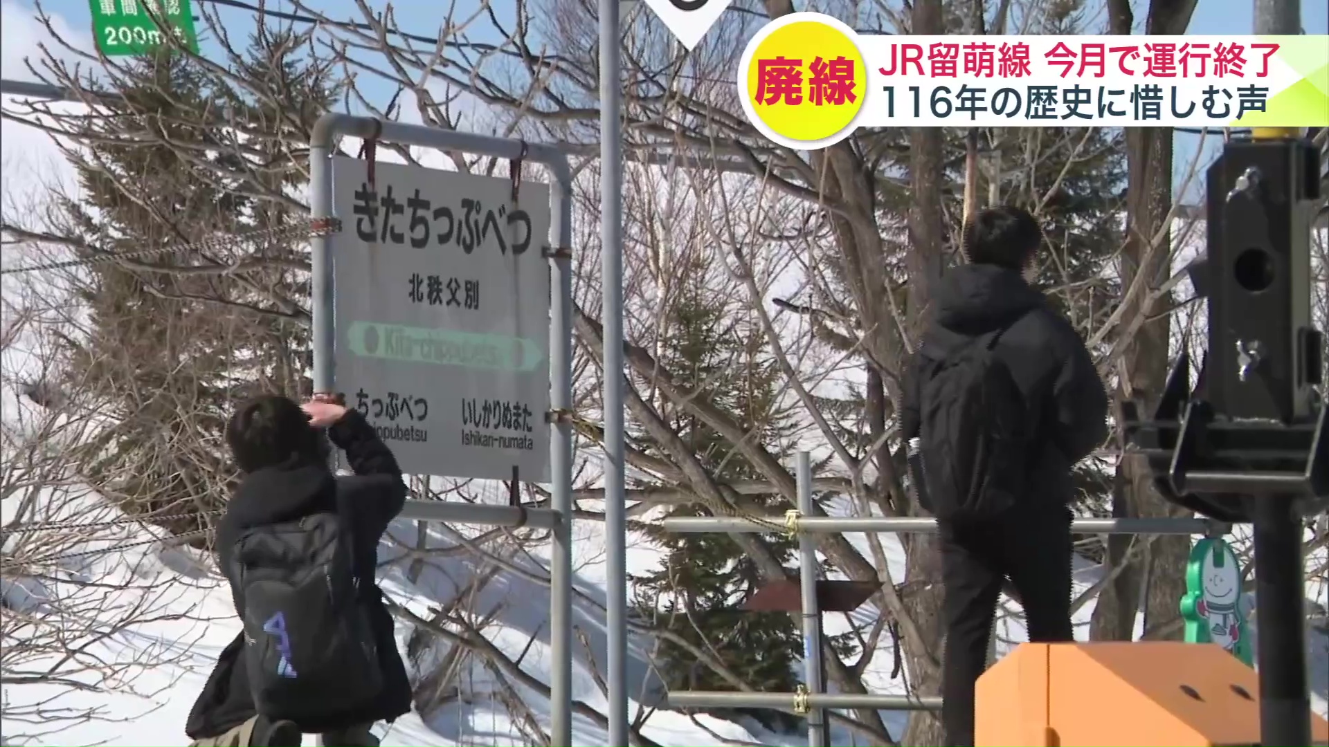 掲示板や駅名の看板などを撮影し別れを惜しむ鉄道ファンたち